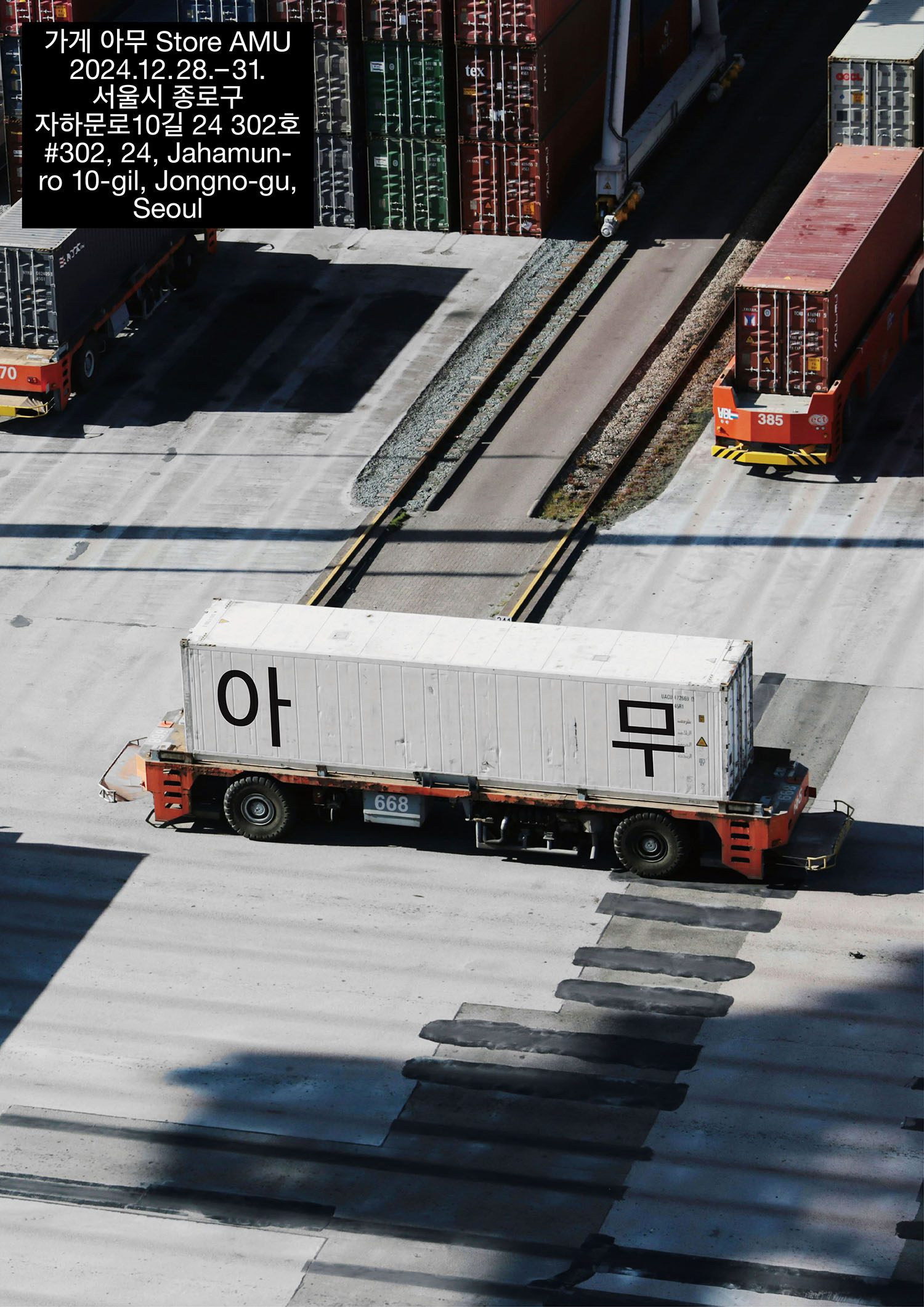 '아무'라는 글자가 검은색으로 쓰여진 흰색 컨테이너를 실은 트럭 사진을 배경인 포스터